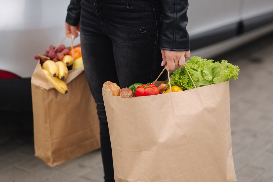 Someone carrying two paper grocery bags full of food