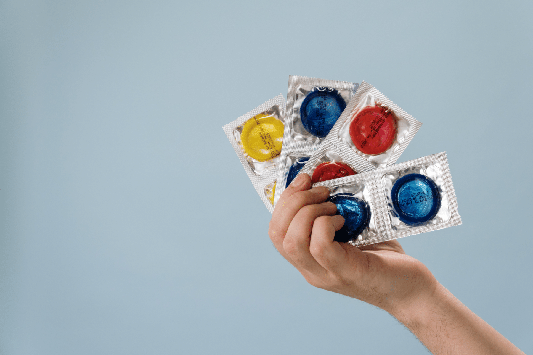 A hand holding multiple condoms.