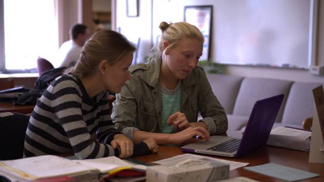 Picture of a student being assisted with a writing assignment by a tutor.